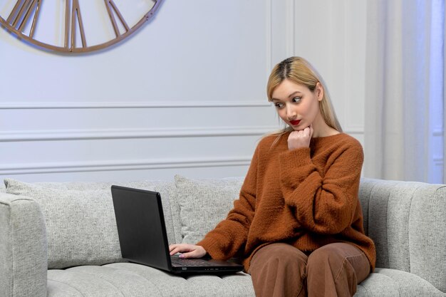 Виртуальная любовь милая блондинка в уютном свитере на дистанционном компьютерном свидании с рукой на подбородке