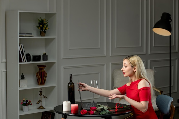 Virtual love cute blonde girl in red dress on distance date with wine holding screen