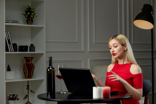 Virtual love cute blonde girl in red dress on distance date with wine talking seriously