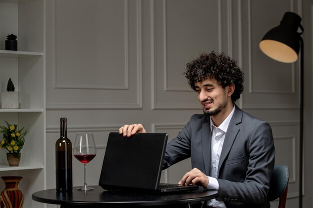 Virtual love handsome cute guy in suit with wine on a distance computer date closing computer