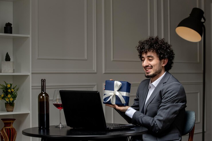 मुफ़्त फोटो virtual love handsome cute guy in suit with wine on a distance computer date holding present box