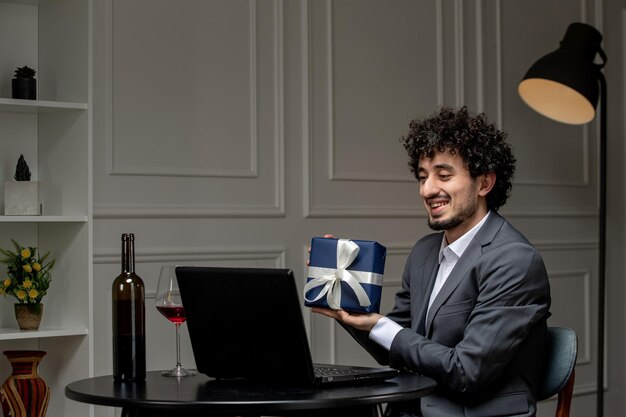 Virtual love handsome cute guy in suit with wine on a distance computer date holding present box