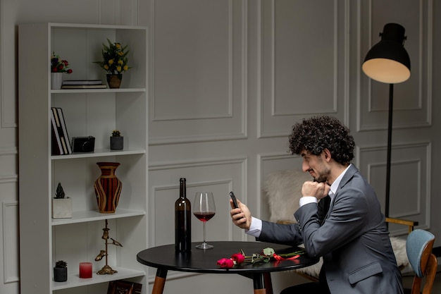 Виртуальная любовь красивый симпатичный парень в костюме с вином на телефонном свидании на расстоянии смотрит вниз