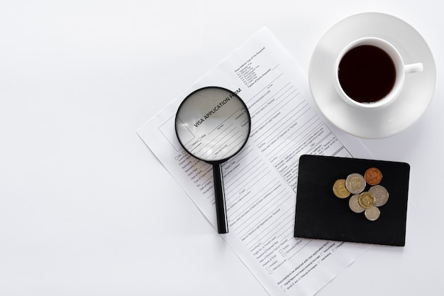 Visa application form documents and a cup of coffee on a white background