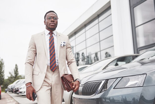 Visiting car dealership. Casual black business man in a suit near the car.