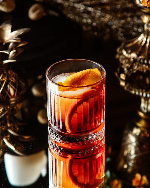 A viski glass with orange cocktail with oranges zest