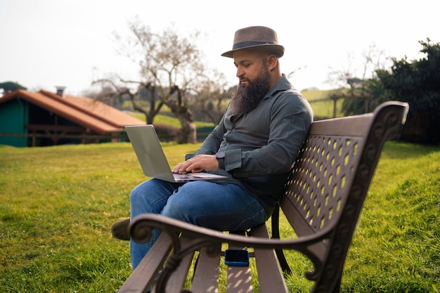 Vista lateral hombre con laptop al aire libre