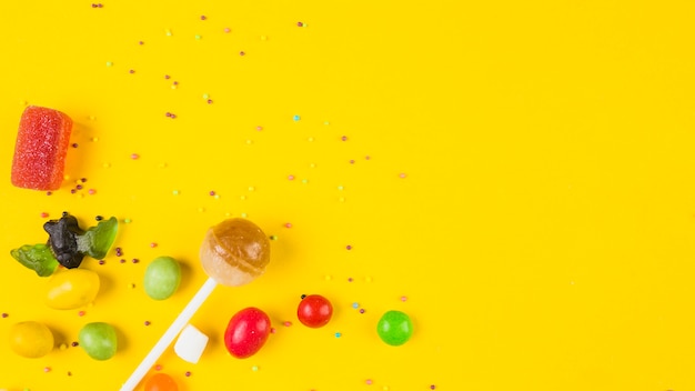 Vivid colorful candies on yellow background