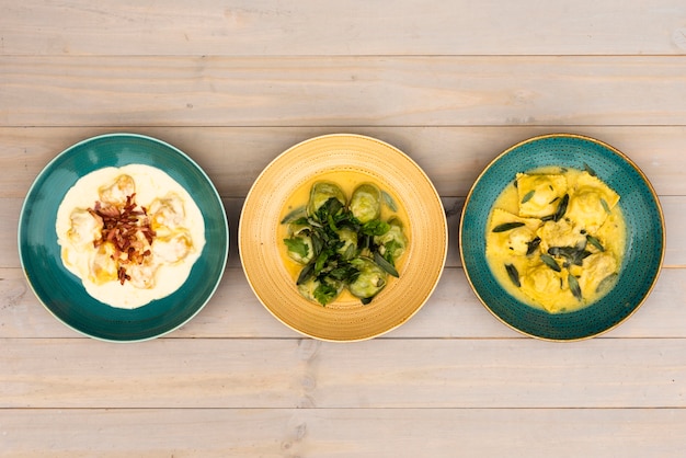 Free photo vivid dishes of ravioli pasta arranged in row on wooden table