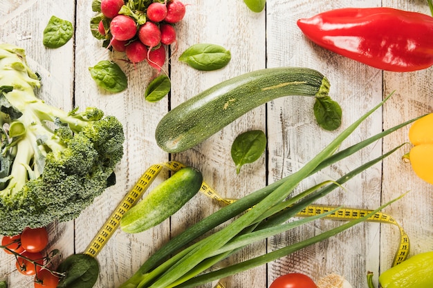 Vivid vegetables and measuring tape on wooden background
