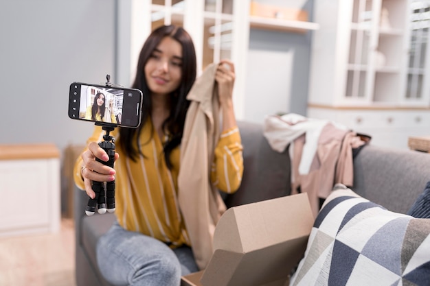 Vlogger дома со смартфоном распаковывает одежду