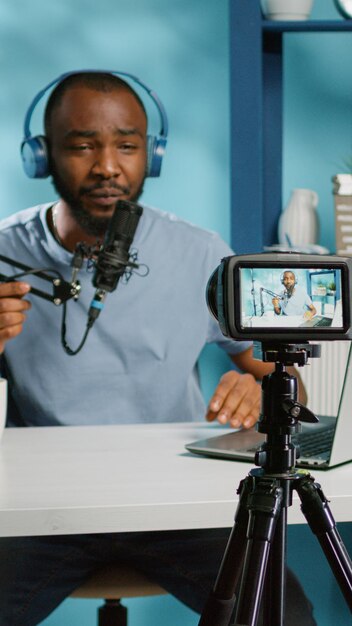 Vlogger는 온라인 팟캐스트용 비디오를 녹화하고 스튜디오에서 노트북을 보고 있습니다. 카메라, 마이크, 헤드폰을 사용하여 채널 구독자를 위한 동영상 블로그를 촬영하는 소셜 미디어 영향력 있는 사람.
