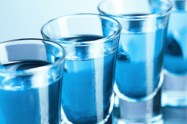 Foto gratuita bicchiere di vodka con ghiaccio sul blu