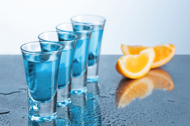 Foto gratuita bicchiere di vodka con ghiaccio sul blu