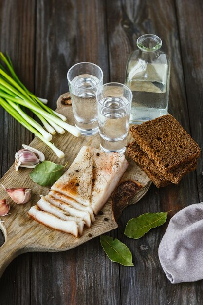 Vodka with lard and green onion on wooden table