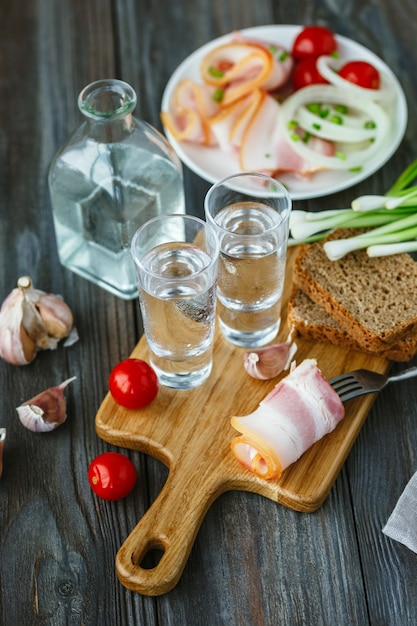 Vodka with lard and green onion on wooden wall.