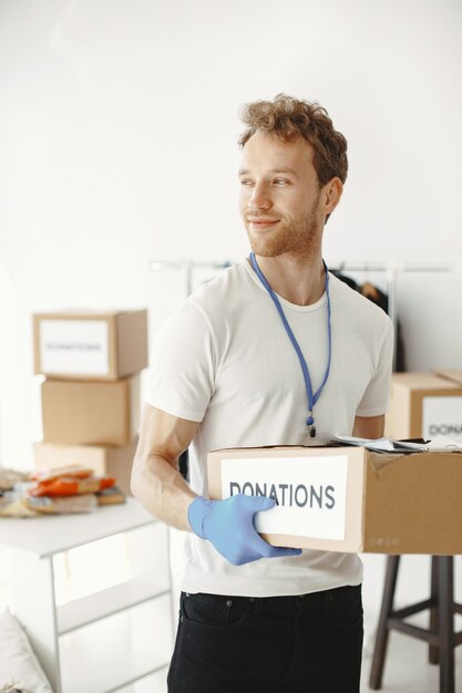 Free photo volunteer collects things from donations. guy packs boxes with things. man compares endowment.