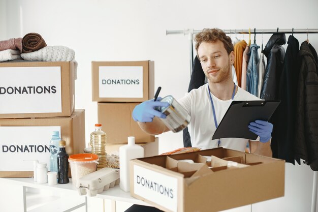 Volunteer collects things from donations. Guy packs boxes with things. Man compares endowment.