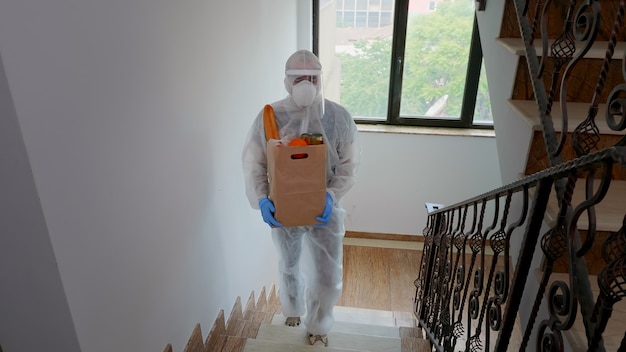 Free photo volunteer delivering food order wearing coverall suit in covid-19 pandemic.