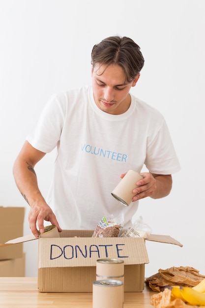 Free photo volunteer placing cans with food in boxes