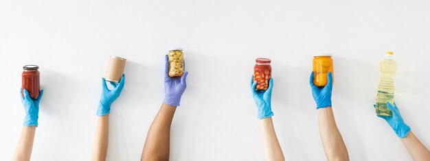 Volunteer's hands with gloves holding provisions for donation