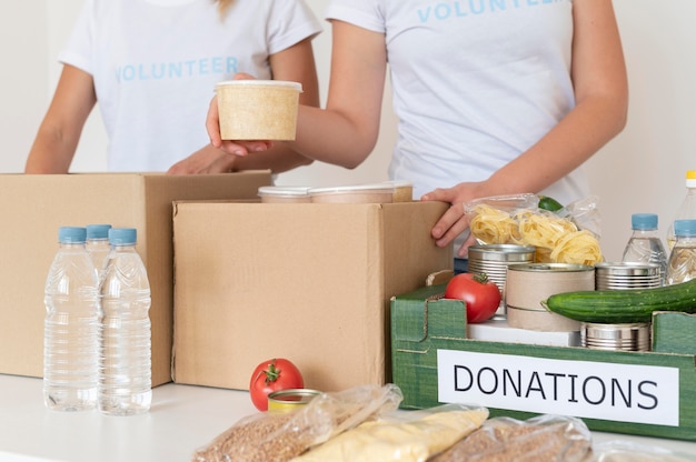 Волонтеры наполняют коробку едой для пожертвований