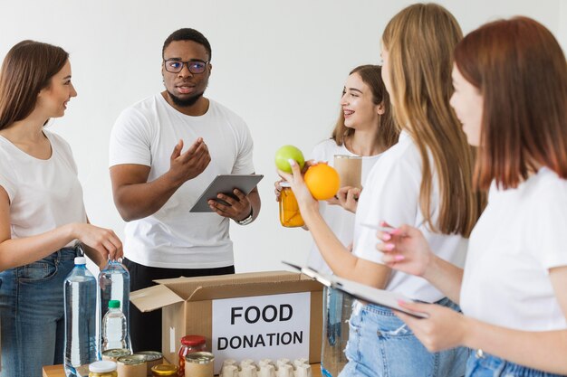 Volunteers preparing boxes with food donations using tablet