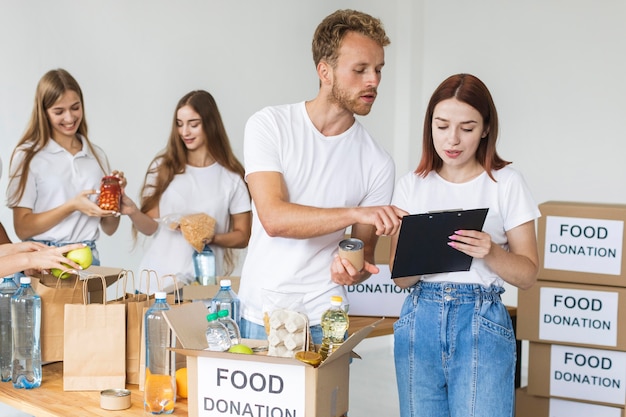 Free photo volunteers putting food in boxes for donations