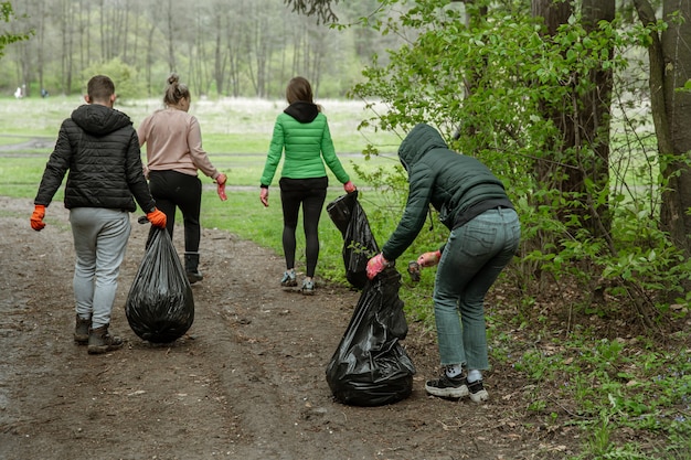 Foto gratuita volontari con sacchi della spazzatura in viaggio nella natura, puliscono l'ambiente.