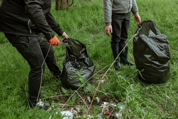 Волонтеры с мешками для мусора в поездке на природу, убирают окружающую среду.