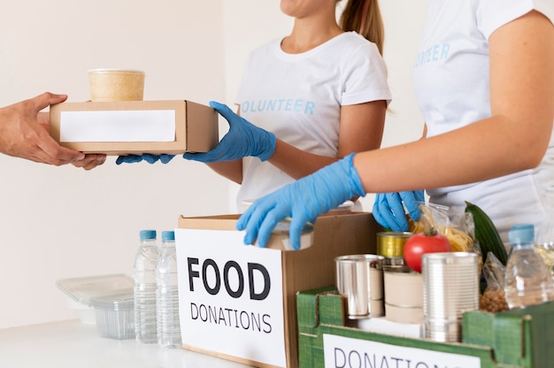 Volunteers with gloves handing boxes with food for donation