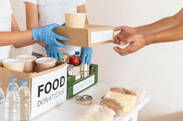 Volunteers with gloves handing boxes with provisions for donation