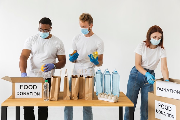 Volunteers with gloves and medical masks preparing food for donation with boxes