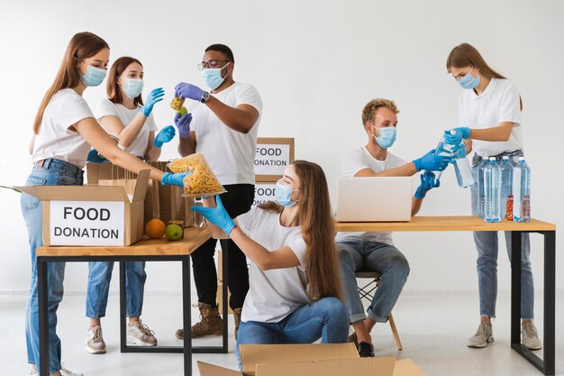 Volunteers with medical masks preparing donation boxes with provisions