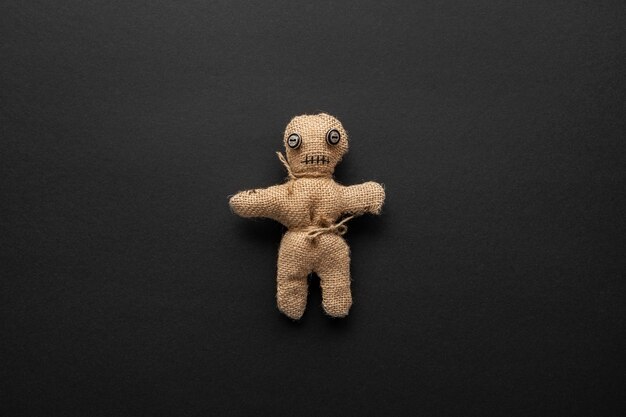 Voodoo doll on dark background flat lay