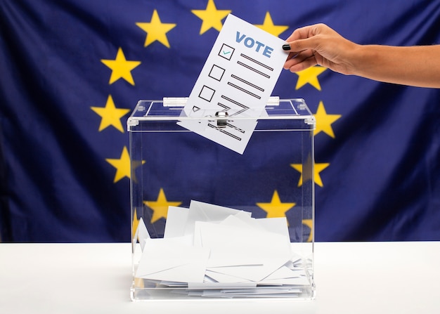 Free photo vote bulletin held by hand and being put into ballot box