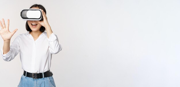 Vr chat Asian girl saying hello in virtual reality glasses smiling enthusiastic concept of communication and future technology white background