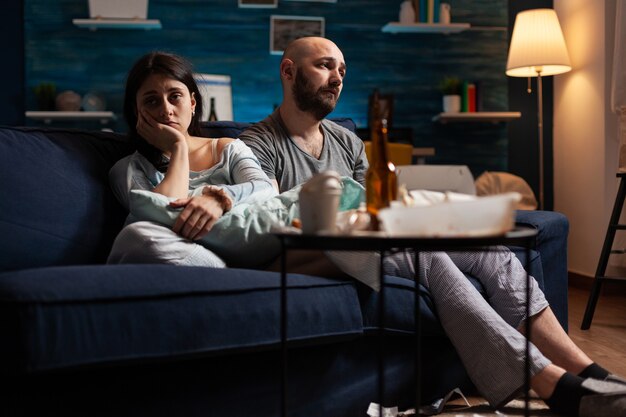 Уязвимая испуганная подавленная разочарованная молодая пара, сидящая на диване