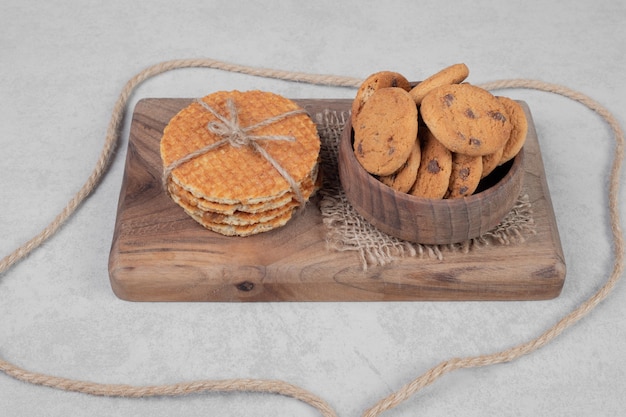 Waffle and bowl of cookies on white surface. High quality photo