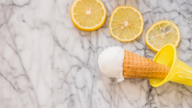 Waffle cone with ice cream near slices of fresh fruits