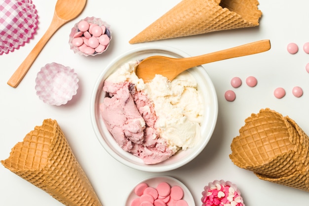 Waffle cones near ice cream in bowl and sprinkles