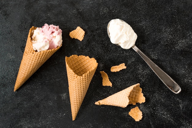 Waffle cones near spoon with ice cream