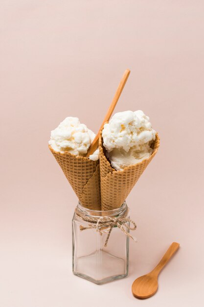 Waffle cones with ice cream in jar near spoon