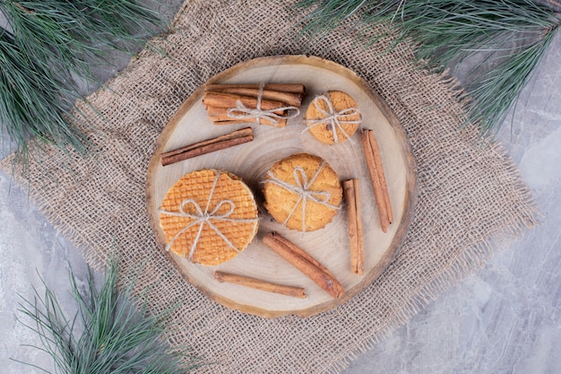 Бесплатное фото Вафельное печенье на деревянной доске с палочками корицы