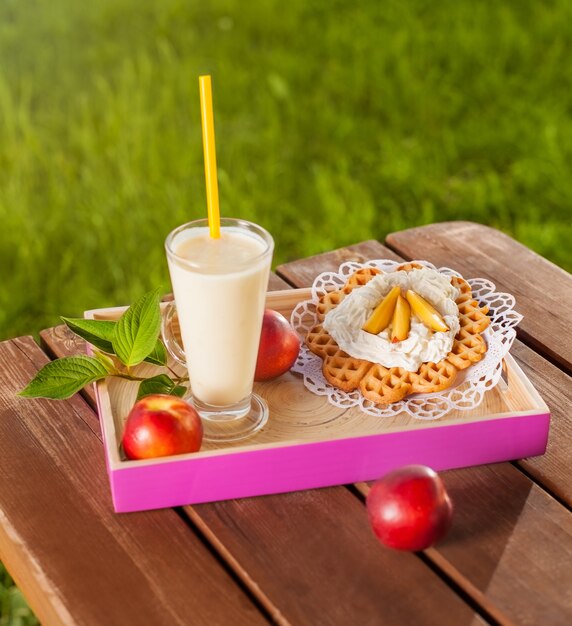 Waffle and milkshake on wooden table in the garden