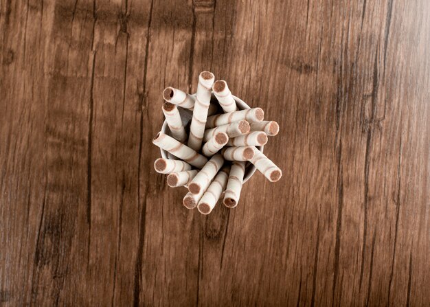 Waffle sticks in a cup on a wooden table.  