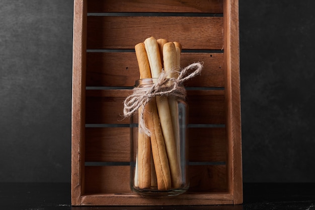 Free photo waffle sticks in a glass jar inside a wooden tray.