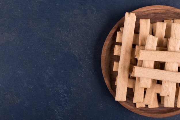 Waffle sticks in a pile in a wooden platter on the right side