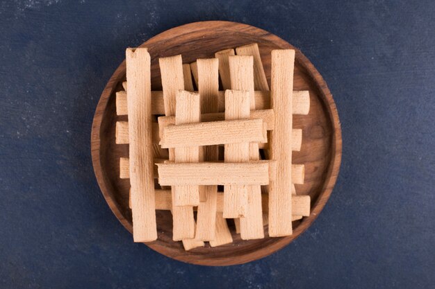 Waffle sticks in a pile in a wooden platter, top view