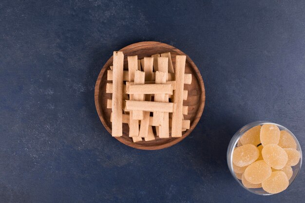 Waffle sticks in a pile in a wooden platter with marmelades aside
